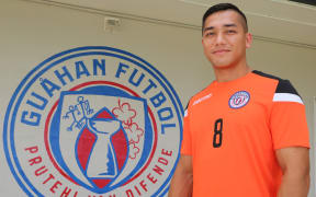 Mark Chargualaf poses alongside the new Guam Football national team badge.