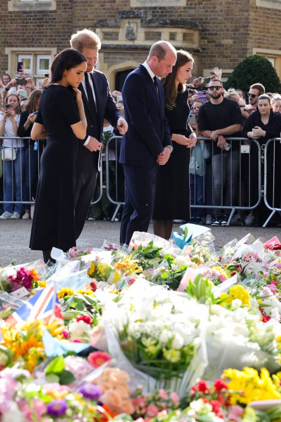 (L-R) Meghan, Duchess of Sussex, Britain's Prince Harry, Duke of Sussex, Britain's Prince William, Prince of Wales and Britain's Catherine, Princess of Wales look at floral tributes laid by members of the public on the Long walk at Windsor Castle on September 10, 2022, before meeting well-wishers. - King Charles III pledged to follow his mother's example of "lifelong service" in his inaugural address to Britain and the Commonwealth on Friday, after ascending to the throne following the death of Queen Elizabeth II on September 8. (Photo by Chris Jackson / POOL / AFP)