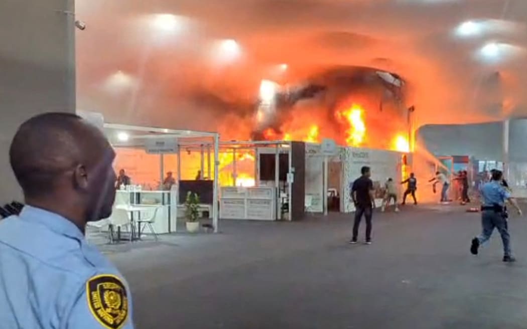 This screen grab taken from AFPTV video footage shows emergency crews battling a fire that broke out at a pavilion inside the venue of the COP30 UN Climate Change Conference in Belem, Para state, Brazil, on November 20, 2025. A fire erupted at a pavilion inside the venue of the UN's climate talks in Brazil on Thursday, prompting panicked delegates to run for the exits, AFP journalists said. Emergency crews rushed to try to put out the blaze as smoke engulfed the corridor. (Photo by AFPTV / AFP)