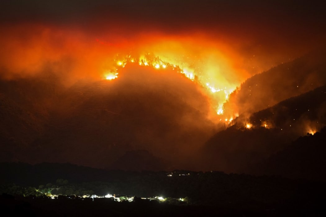 A picture taken from the village of Atajate shows the flames of a wildfire burning a forest area behind the village of Alpandeire on 12 September 12.