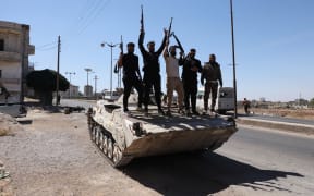 Syria's security forces stand on a tank in the predominantly Druze city of Sweida on July 15, 2025, following clashes between Bedouin tribes and Druze fighters. Syrian government forces entered the majority Druze city of Sweida on July 15, 2025, the interior ministry said, aiming to end clashes with Bedouin tribes that have killed nearly 100 people. (Photo by Bakr ALkasem / AFP)