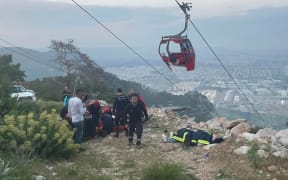 This handout photograph taken and released on April 12, 2024 by Turkish news agency DHA (Demiroren News Agency) shows rescue teams conducting a rescue operation and helping injured people after a cable car cabin crashed into a fallen cable pole in Konyaalti district of Antalya. (Photo by Handout / DHA (Demiroren News Agency) / AFP) / - Turkey OUT / RESTRICTED TO EDITORIAL USE - MANDATORY CREDIT "AFP PHOTO /  DHA (Demiroren News Agency) " - NO MARKETING NO ADVERTISING CAMPAIGNS - DISTRIBUTED AS A SERVICE TO CLIENTS