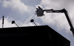 Firefighters pour water on to the roof  of the Loafers Lodge hostel, Newtown, Wellington.