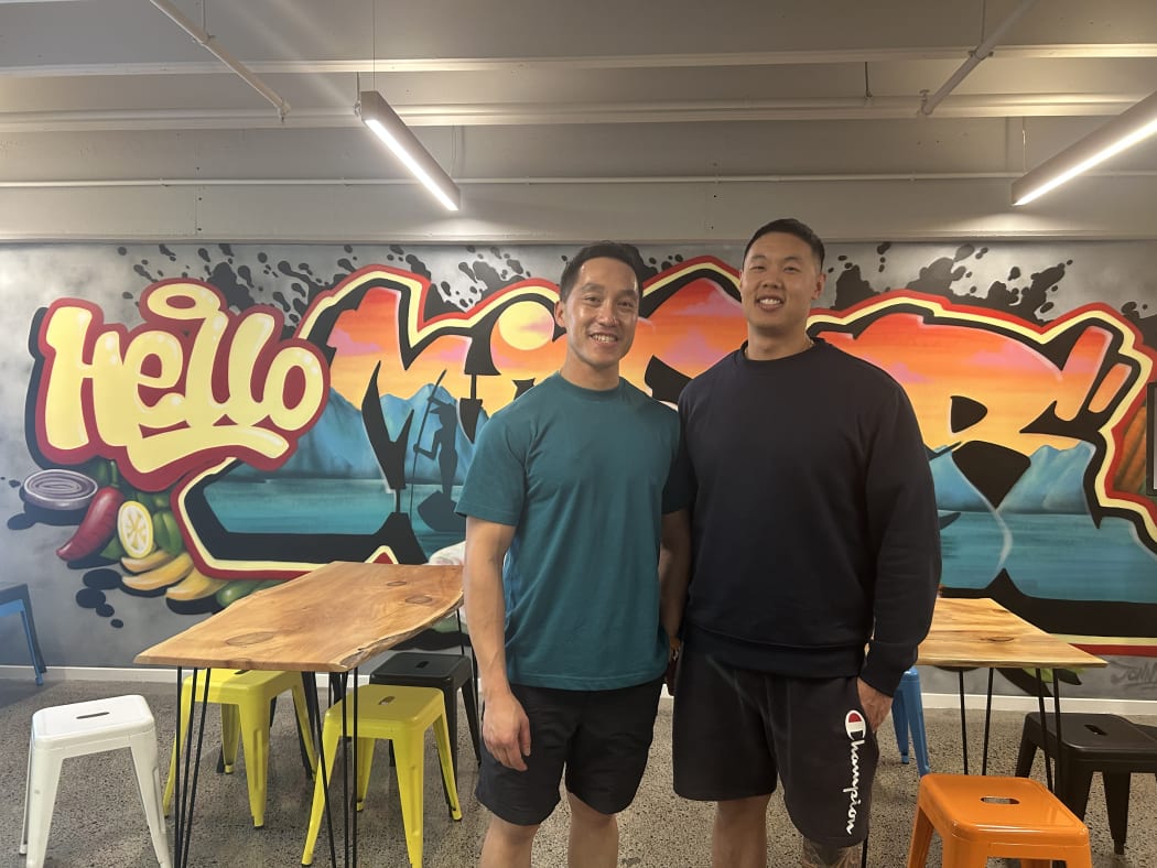 A photo of two people standing in front of a mural in a restaurant.