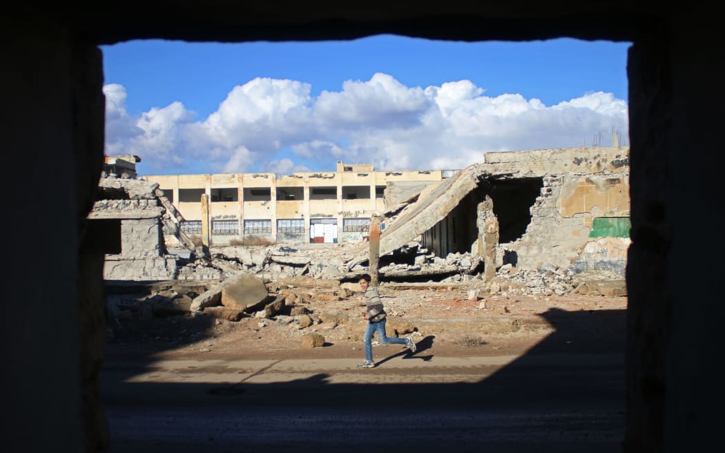 A Syrian boy runs past the rubble of destroyed buildings in the rebel-held area of Daraa, in southern Syria.