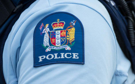 Close up of a police officer at an incident on a residential street. 6 July 2016.
