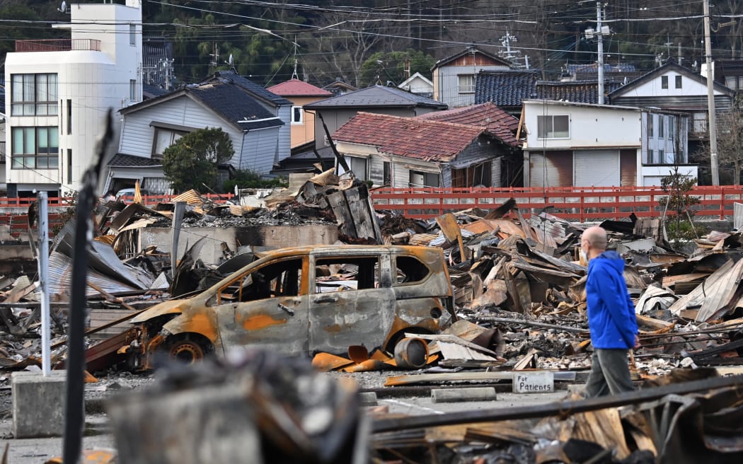 A man walks past the ruins of a shopping district in the city of Wajima, on 4 January, 2024, after a major 7.5 magnitude earthquake struck on New Year's Day.