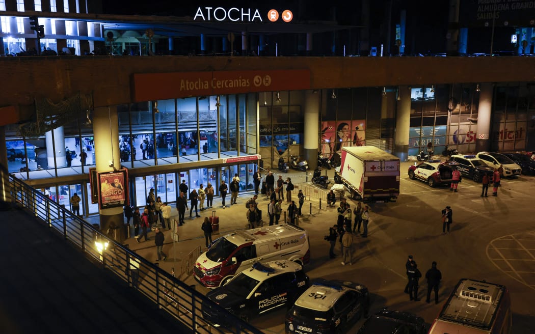Ambulances and police cars are parked outside Atocha station as many travelers prepare to spend the night inside, following a massive power cut affecting the entire Iberian peninsula and the south of France, in Madrid on April 28, 2025. Spanish Prime Minister Pedro Sanchez said today authorities were not ruling out any  cause for the widespread blackout across the Iberian pensisula. "All potential causes are being analysed, I insist, without ruling out any hypothesis, any possibility," Sanchez told a press conference, 11 hours after Spain and Portugal were  plunged into darkness for reasons that had yet to be determined. (Photo by OSCAR DEL POZO / AFP)