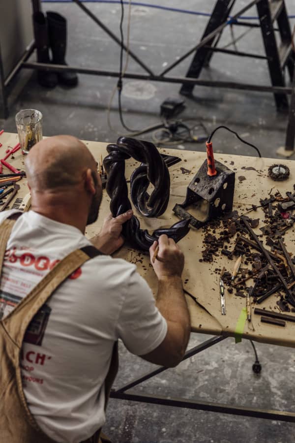 A bald man works with brown tools on a wooden table.