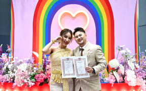 Kevin Pethai Thanomket (left) and Maple pose for pictures after registering their same-sex marriage in Bangkok on 23 January, 2025, as scores of same-sex and transgender couples married in Thailand on January 23 as the kingdom's equal married following a law change.