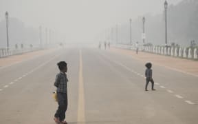 Children walk along Rajpath near India Gate under heavy smog conditions in New Delhi on November 9, 2020. (Photo by Sajjad HUSSAIN / AFP)