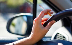 Smoking a cigarette in a car.