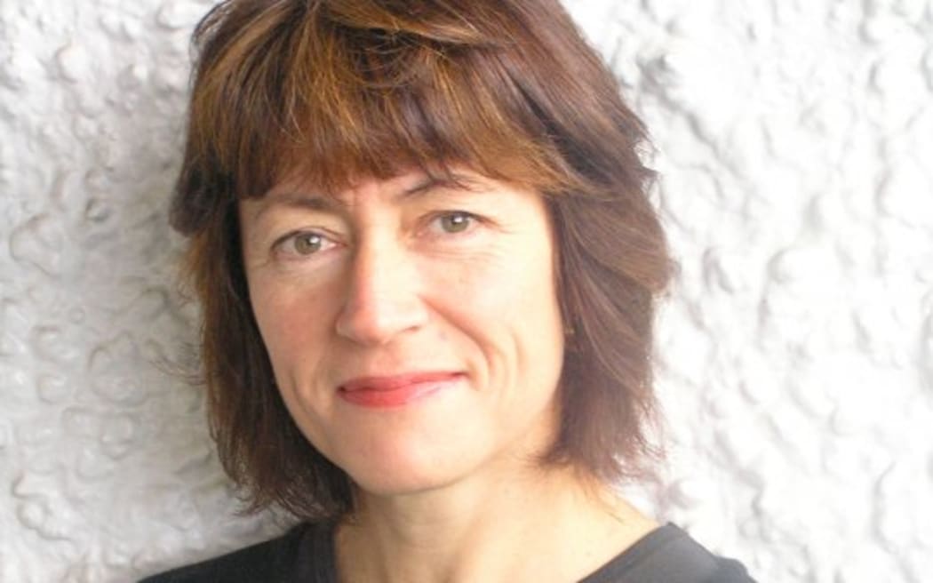 Jennie Miller is wearing a black top and standing in front of a wall. It's a head and shoulders shot.