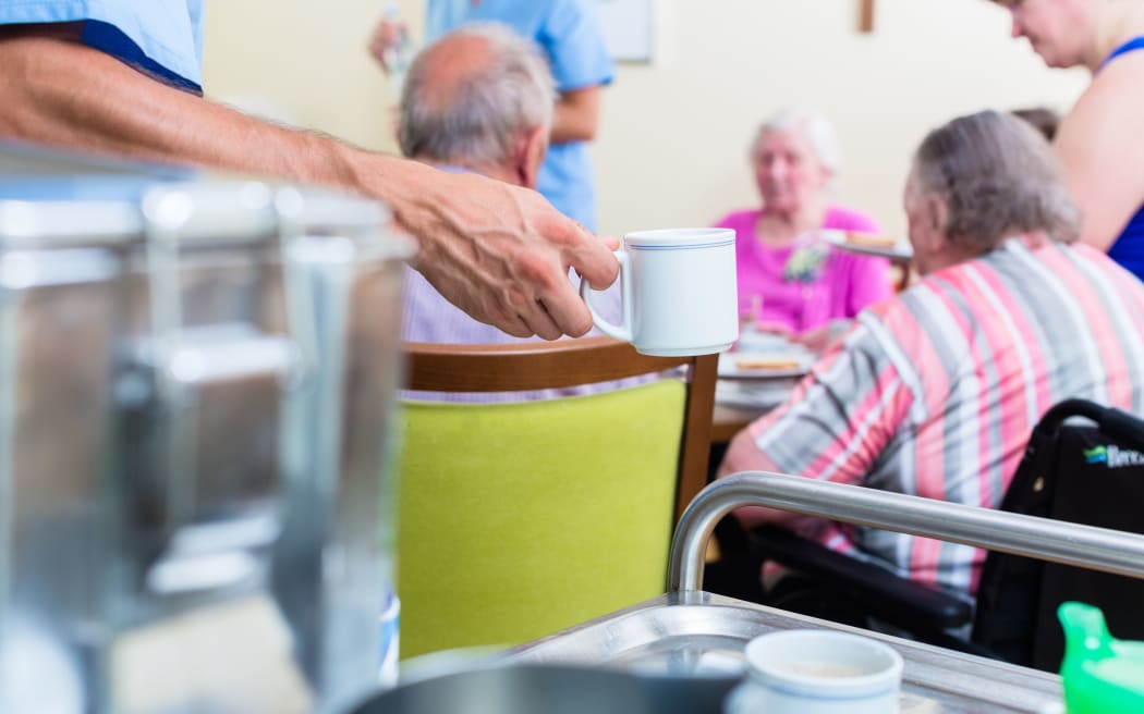 Nurse serving food in rest home for elderly.