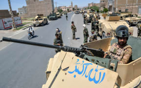 (FILES) In this file photo taken on August 1, 2021, Afghan National Army commando forces stand guard along a road amid ongoing fighting between Taliban and Afghan security forces in the Enjil district of Herat province.