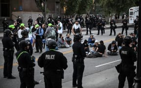 Police officers surround arrested protesters following a demonstration against federal immigration operations near Los Angeles City Hall in Los Angeles on June 11, 2025. Over 1,000 people massed in America's second biggest city for a sixth day of protests, with the crowd peaceful as they marched through the streets. A second night of curfew was in place as city leaders try to get a handle on the after-dark vandalism and looting that scarred a few city blocks in the 500-square-mile (1,300 square kilometers) metropolis. (Photo by RONALDO SCHEMIDT / AFP)