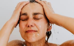 A woman washes her hair in the shower