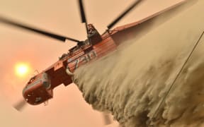 A helicopter drops fire retardent to protect a property in Balmoral 150km southwest of Sydney.