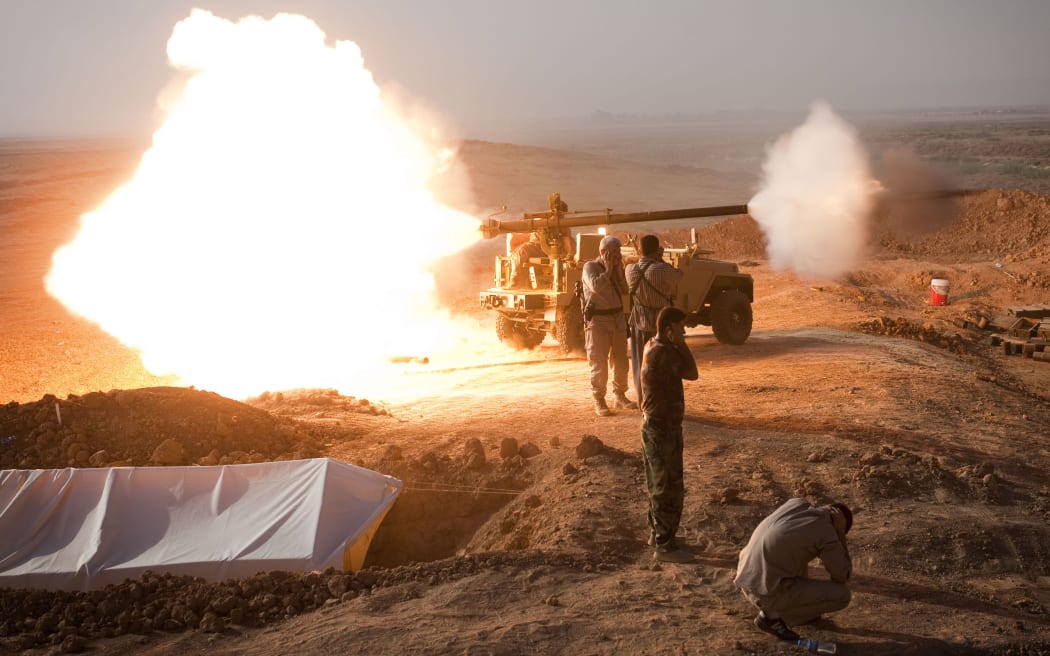 Iraqi Kurdish Peshmerga fighters fire towards Islamic State (IS) positions.