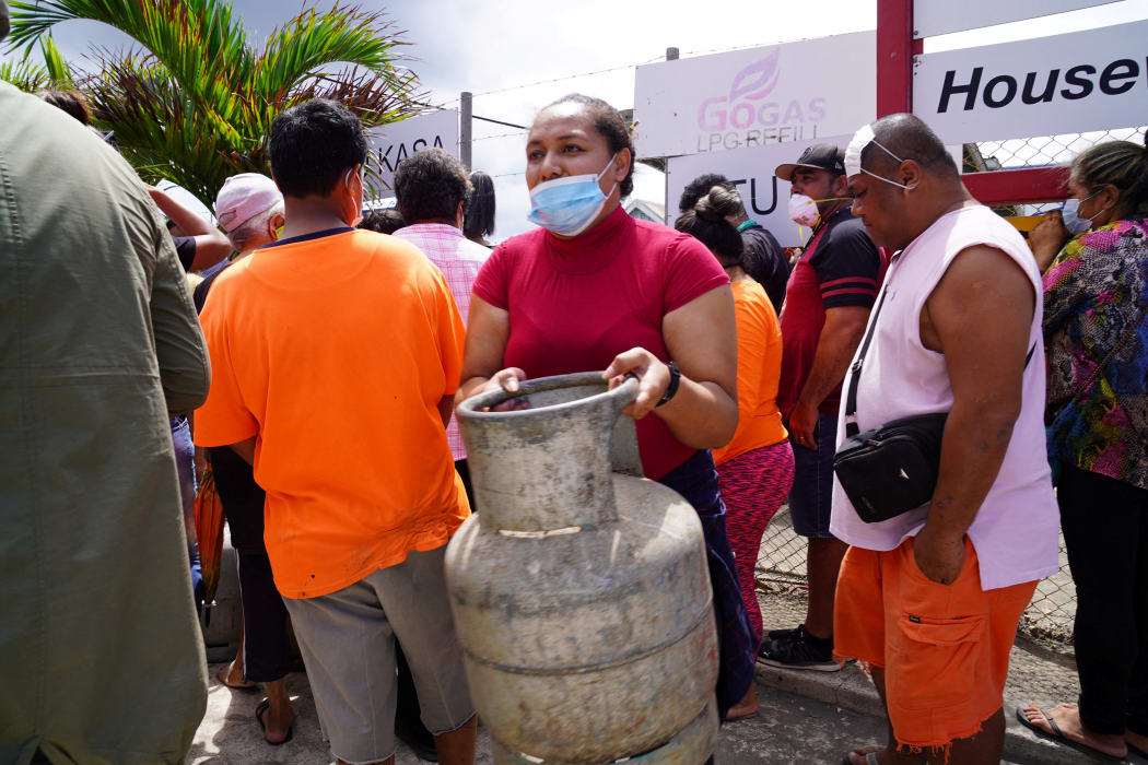 A woman carries a refilled gas container in the centre of the capital Nuku'alofa ahead of the country's first lockdown on February 2, 2022