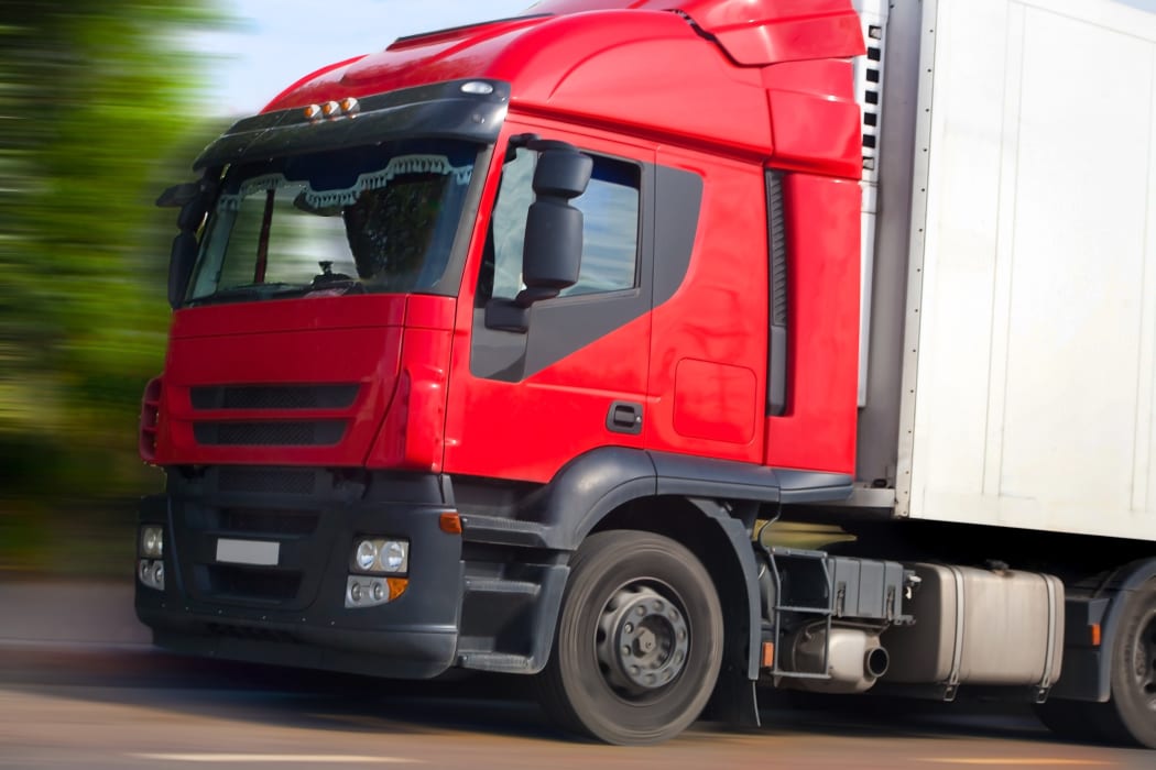 A truck with a red cab picks up speed.