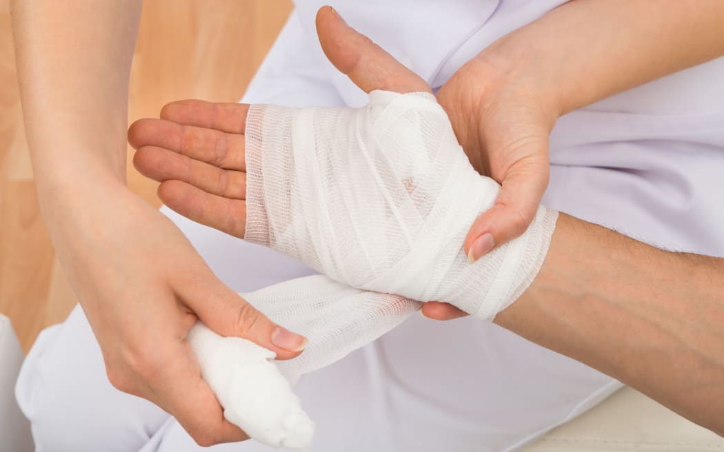 High Angle View Of A Female Doctor Bandaging Patient's Hand