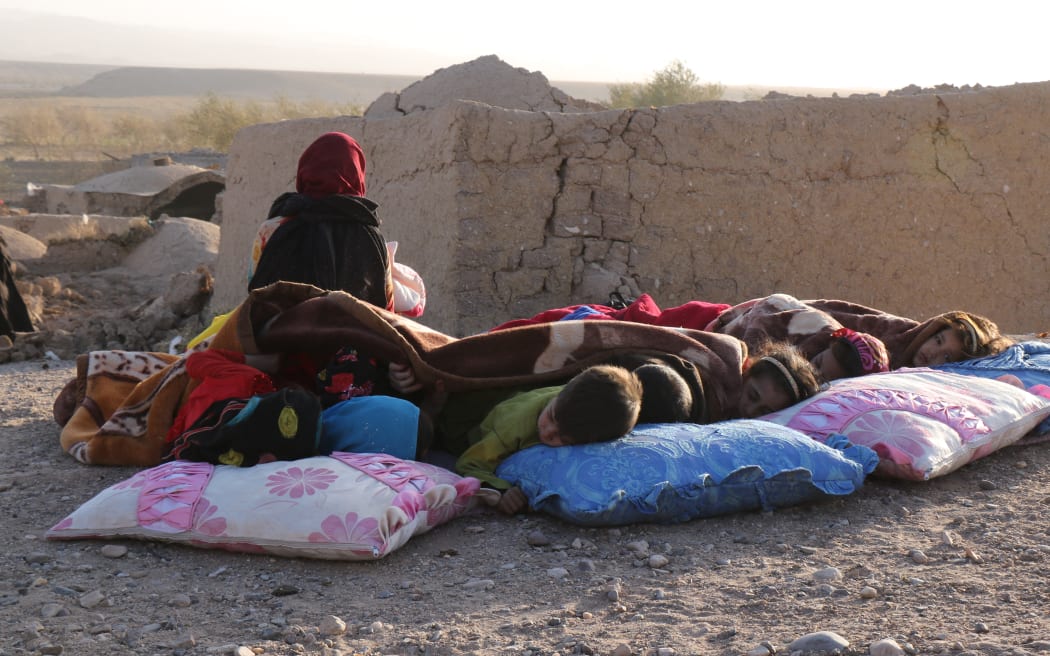 Afghan children rest under a blanket beside damaged houses after earthquake in Sarbuland village of Zendeh Jan district of Herat province on October 7,2023 (Photo by Mohsen KARIMI / AFP)