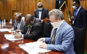 Seated: Papua New Guinea's State Enterprises Minister, Sasindran Muthuvel (left), Prime Minister James Marape (centre) and the chairman of Fortescue Metals Group of Australia, Andrew Forrest, sign an agreement, Port Moresby, 1st September 2020.