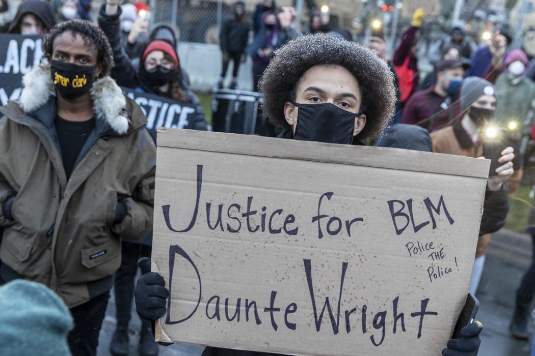 A protester holds a sign reading "Justice for Daunte Wright" during a rally outside the Brooklyn Center police station to protest the death of Daunte Wright who was shot and killed by a police officer in Brooklyn Center, Minnesota on 13 April 2021.