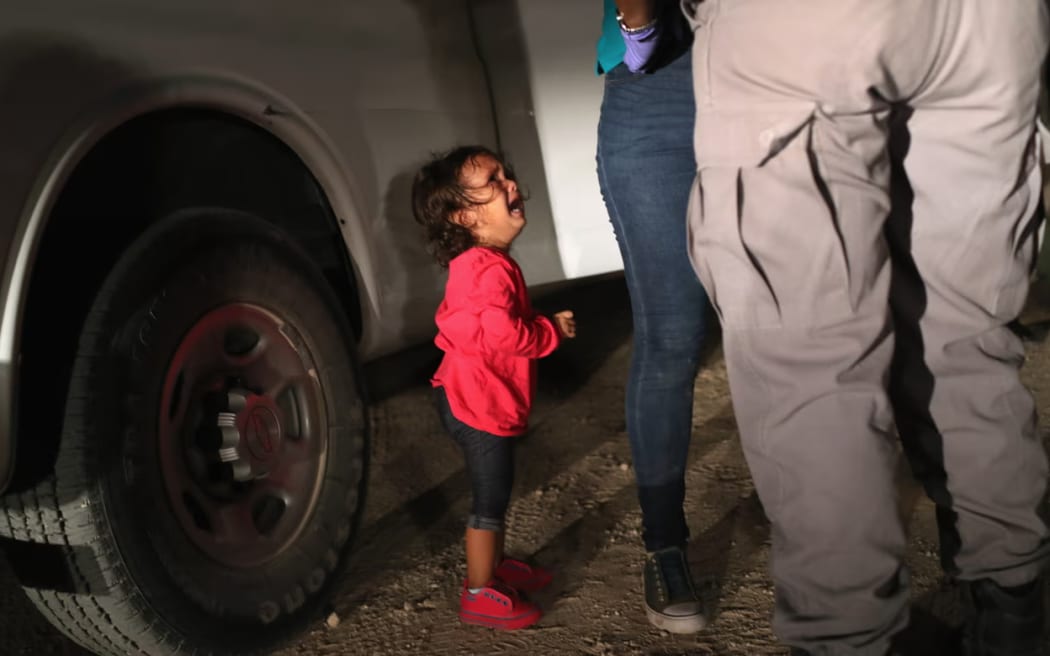 A two-year-old Honduran asylum seeker cries as her mother is searched and detained near the US-Mexico border, in McAllen, Texas.