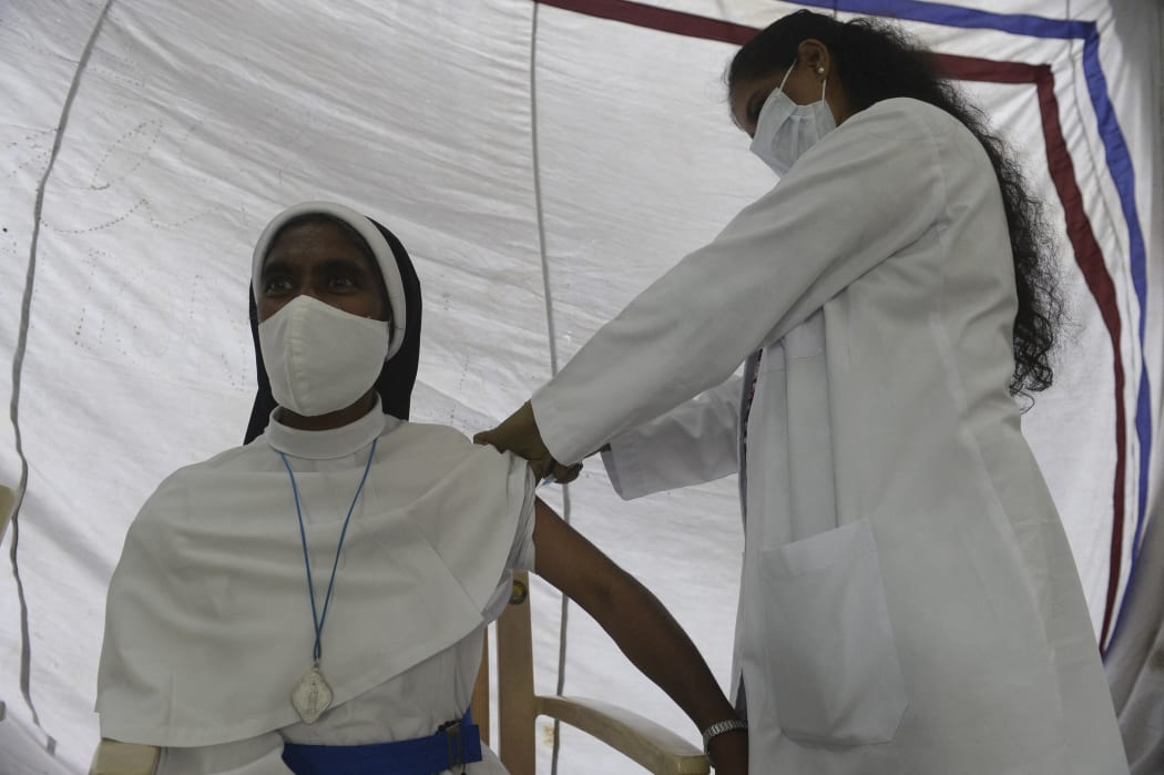 A health worker inoculates a Catholic nun with the first dose of the Covaxin vaccine against the Covid-19 coronavirus during a vaccination drive at Saint Mary's Basilica in Secunderabad, the twin city of Hyderabad on August 19, 2021.