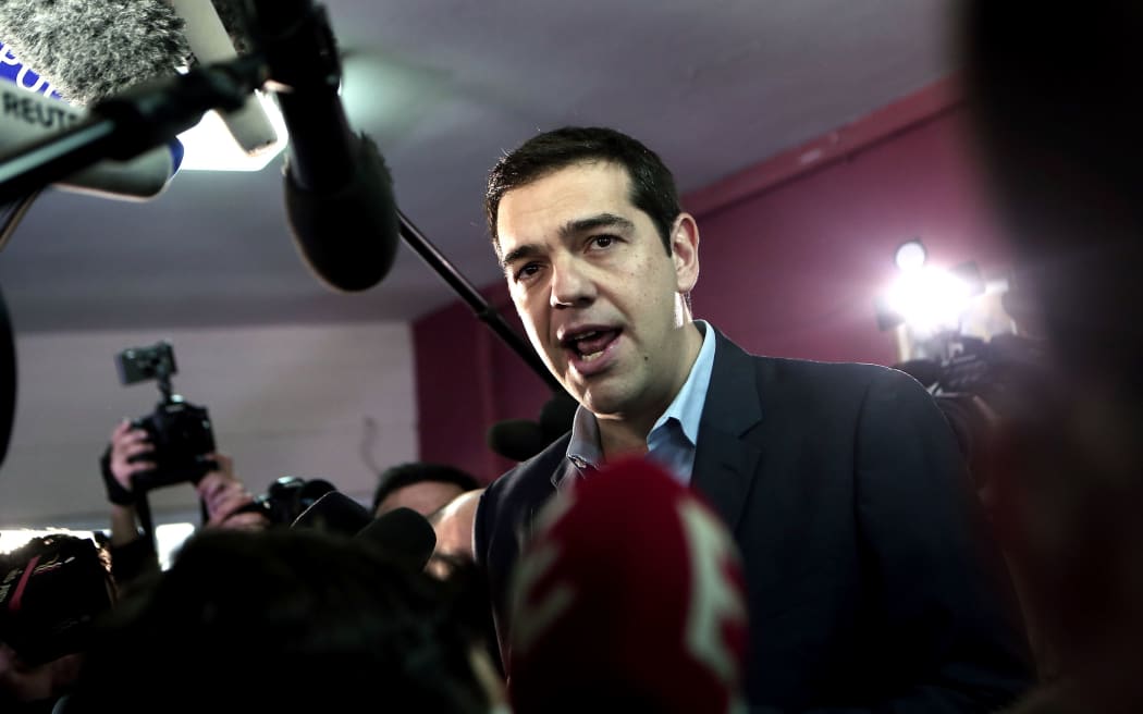The leader of Greece's left-wing Syriza party Alexis Tsipras (C) talks to journalists after voting at a polling station in Athens in January 2015.
