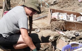 Emma Tuck searches through the silt for belongings.