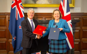 A man and a woman hold folders and shake hands.