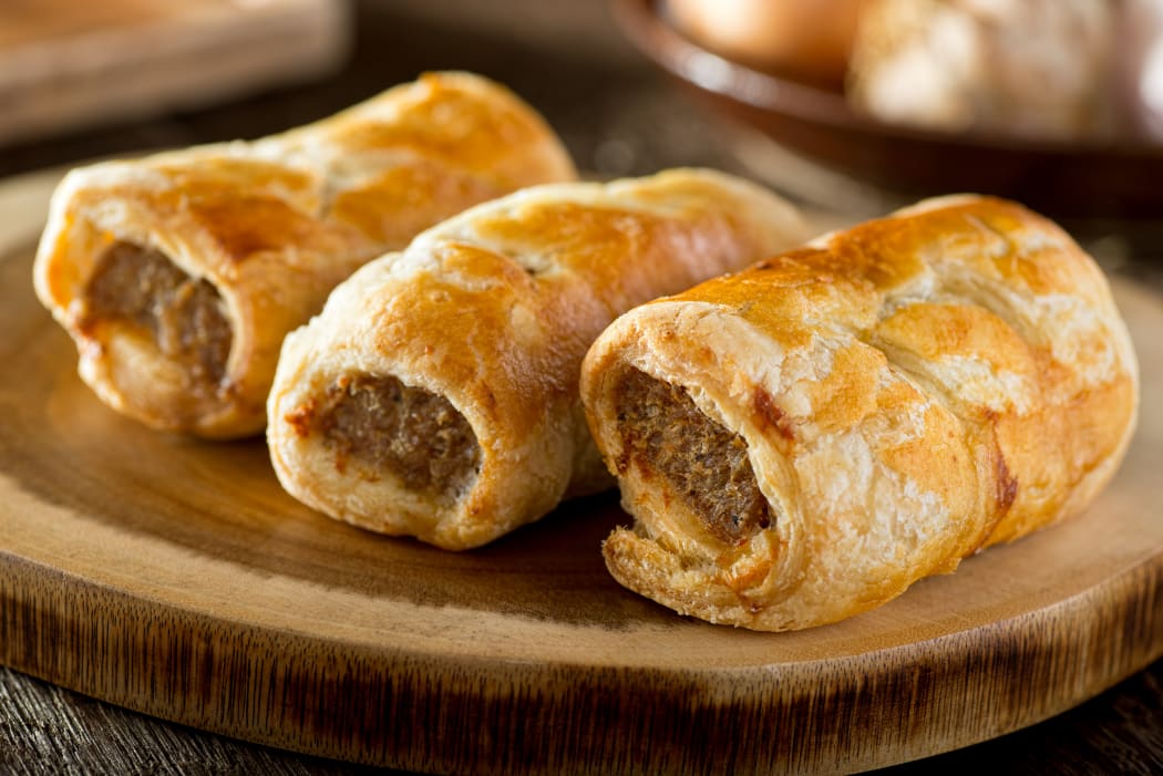 Delicious homemade sausage rolls on a wooden serving platter.