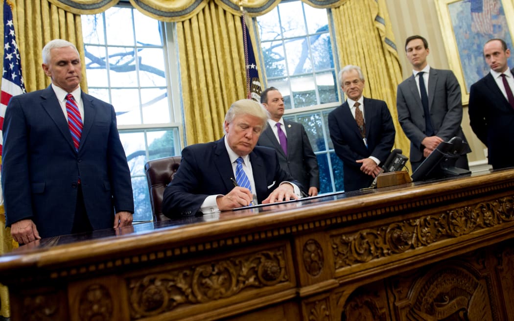 Donald Trump, seated, signed three executive orders on Monday, including one banning any US-funded organisations from speaking about abortion.