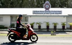 This photo taken on June 15, 2025 shows a person riding past the Parliament of the Cook Islands on the main island of Rarotonga. New Zealand’s government halted aid to close partner the Cook Islands on June 19 because of a row over agreements the Pacific island nation struck with China. (Photo by William WEST / AFP)