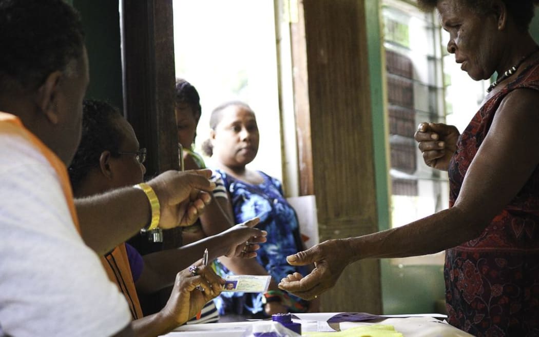 Election officials assist a women preparing to cast her vote during the 2014 elections.