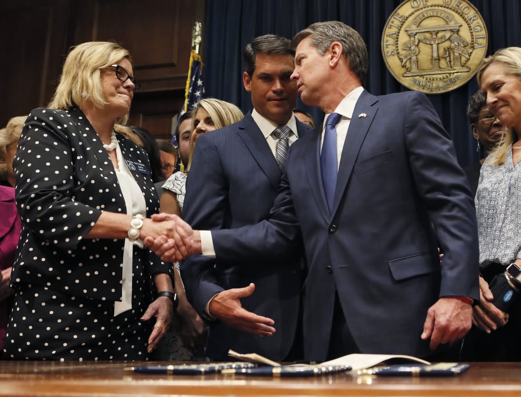 Georgia's Republican governor Brian Kemp (right) shakes hands with state Senator Renee Unterman after signing legislation banning abortions once a foetal heartbeat can be detected.