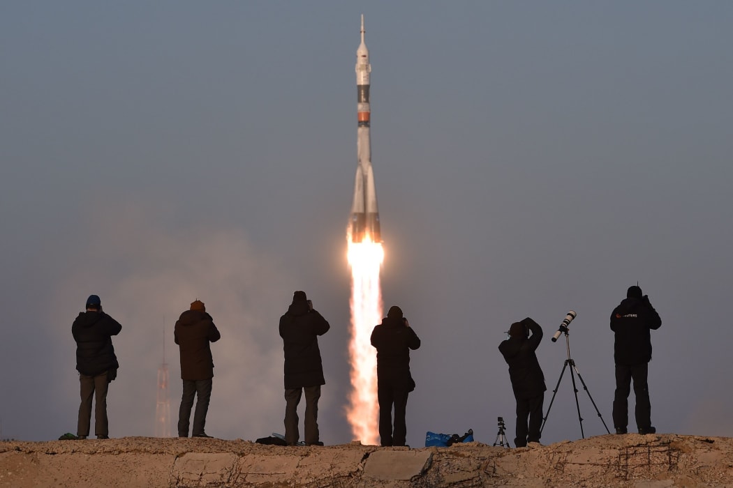 Photographers take pictures as Russia's Soyuz spacecraft blasts off.