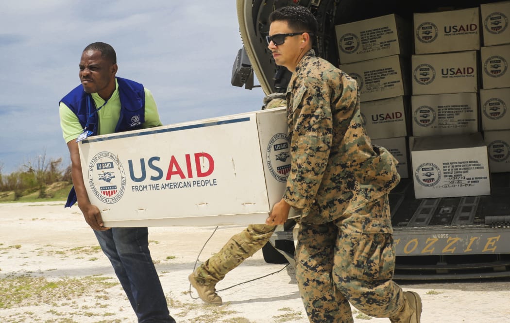 This October 9, 2016 US Marine Corps handout photo shows Cpl. Steven Arroyo, a heavy equipment mechanic with Marine Wing Support Detachment 31, assisting an International Organization for Migration representative in carrying supplies at Jeremie, Haiti.