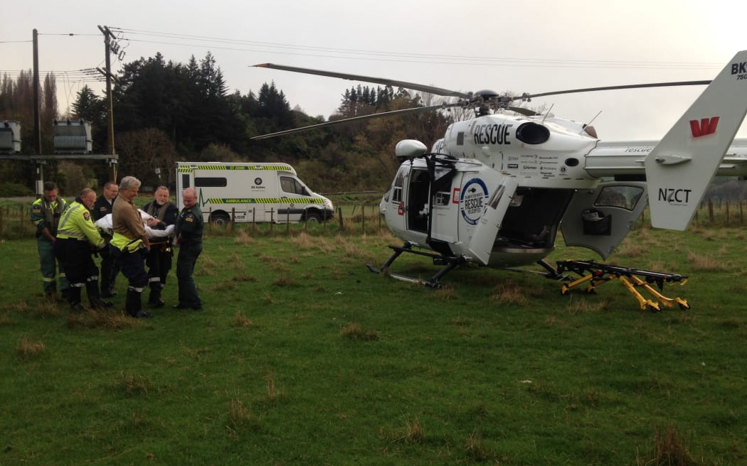 The injured truck driver is carried to a waiting rescue helicopter.