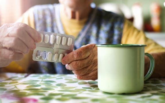 A person about to consume cold medications with a cup of tea