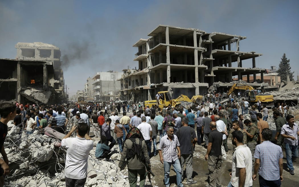 Syrians gather at the site of a bomb attack in Syria's northeastern city of Qamishli.
