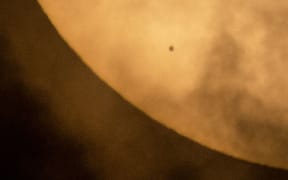 The planet Mercury is seen from NASA Headquarters in Washington DC, in silhouette, lower left, as it transits across the face of the sun.