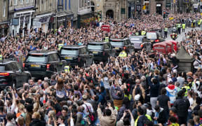 Members of the public watch the hearse carrying the coffin of Queen Elizabeth II, as it is driven through Edinburgh towards the Palace of Holyroodhouse, on September 11, 2022.