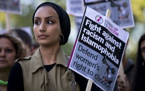 A woman wearing a headscarf joins a demonstration organised by "Stand up to Racism" outside the French Embassy in London on August 26,