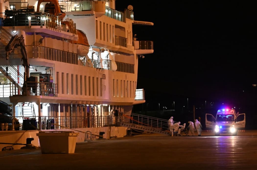 Passengers of the COVID-19 coronavirus-stricken Australian liner Greg Mortimer disembark in personal protective equipment from the cruise ship at Montevideo's port from where Australian and New Zealander passengers will be directly escorted to the international airport