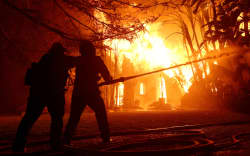 ALTADENA, CALIFORNIA - JANUARY 08: Los Angeles County firefighters spray water on a burning home as the Eaton Fire moved through the area on January 08, 2025 in Altadena, California. Fueled by intense Santa Ana Winds, the Palisades Fire has grown to over 2,900 acres and 30,000 people have been ordered to evacuate while a second fire has emerged near Eaton Canyon in Altadena.   Justin Sullivan/Getty Images/AFP (Photo by JUSTIN SULLIVAN / GETTY IMAGES NORTH AMERICA / Getty Images via AFP)
