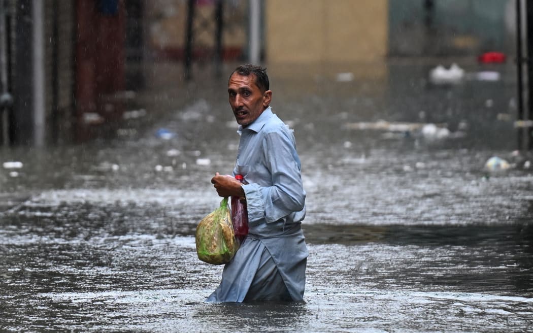A man wades through a flooded street during heavy monsoon rains in Rawalpindi on 17 July, 2025.